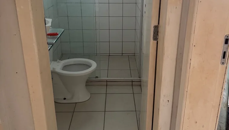 O mesmo banheiro depois da limpeza pós-obra: azulejo, box e louça brancos e sem marca.
