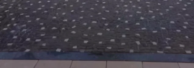 A mesma entrada de garagem depois da revitalização, com a pedra escura e o mosaico visível.