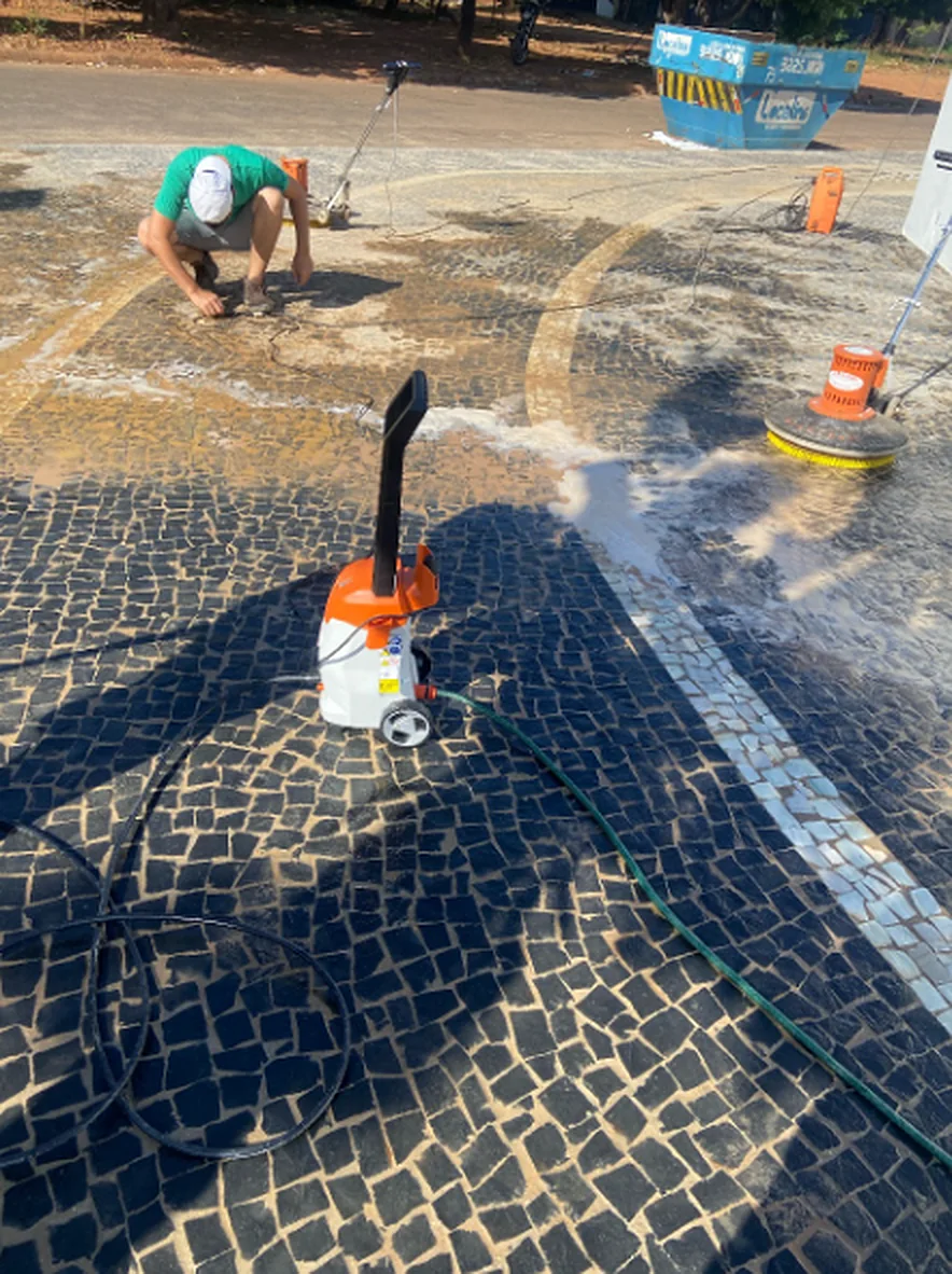 Equipe da Ermes em campo, tratando um calçadão de pedra portuguesa com rotativa e lavadora de alta pressão.