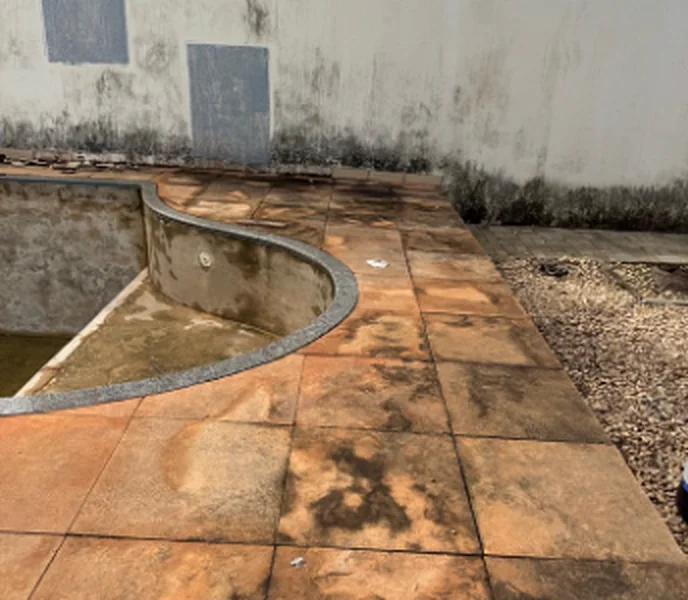 Piso de área de piscina com manchas escuras e marcas de obra espalhadas pelo porcelanato.